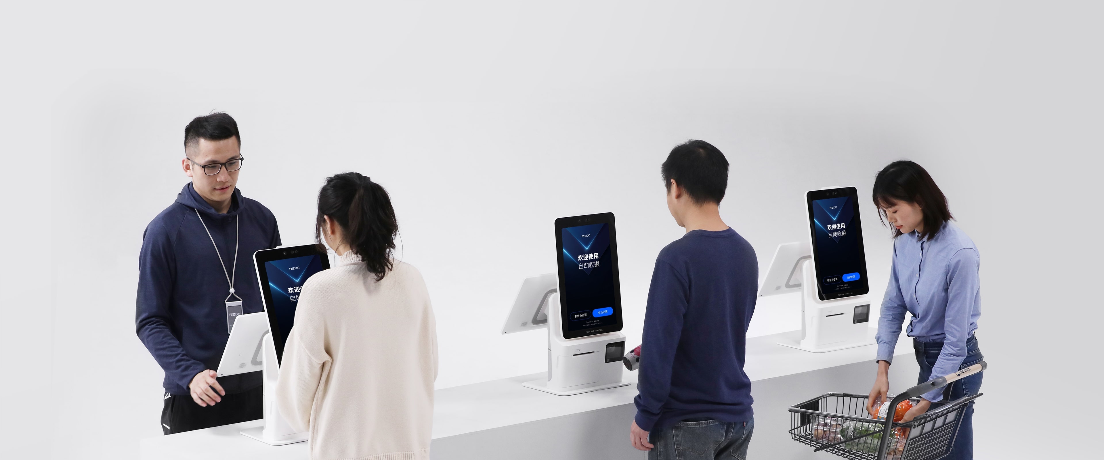 Customers paying for groceries at Sunmi K2 Mini self-checkout kiosks while staff assist nearby