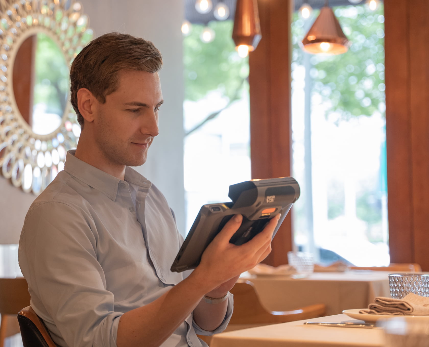 Staff using the Sunmi V3 MIX to take an order tableside in a restaurant